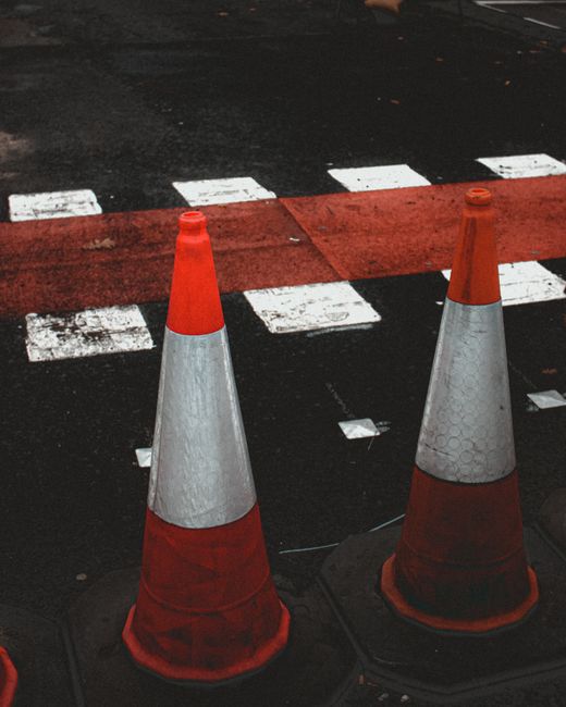 Nighttime scene of a residential street in Brentford with road closure barriers and orange traffic signs, indicating ongoing street-closure rules for local traffic management. Streetlights cast a warm